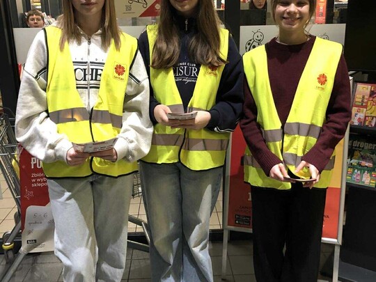 Uczennice klasy 8b w kamizelkach odblaskowych, rozdające ulotki akcji Caritas "Tak, Pomagam"