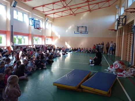 Uczniowie zebrani na sali gimnastycznej obserwują pokaz kung fu