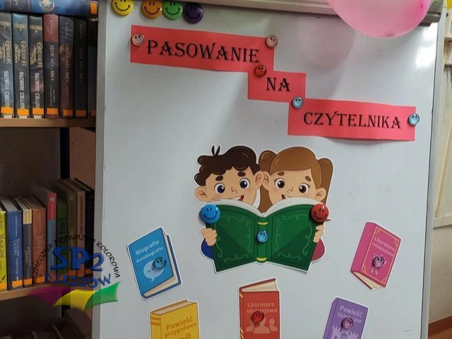 Zdjęcie przedstawia tablicę, na której są dzieci czytające książkę i książki.