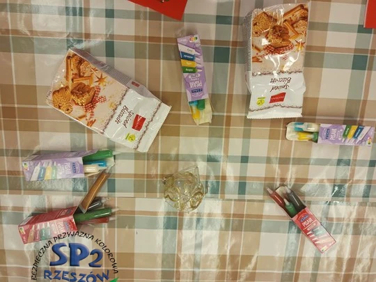Na stole leżą dwa opakowania ciasteczek/pierniczk&oacute;w i pięć opakowań pisak&oacute;w służących do ich ozdabiania.