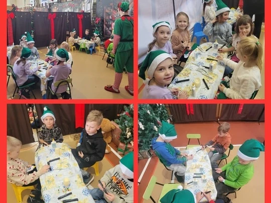 Dzieci siedzą przy stolikach i ozdabiają drweniane reniferki.