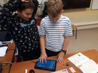 Uczniowie programują na tablecie robota Photon.